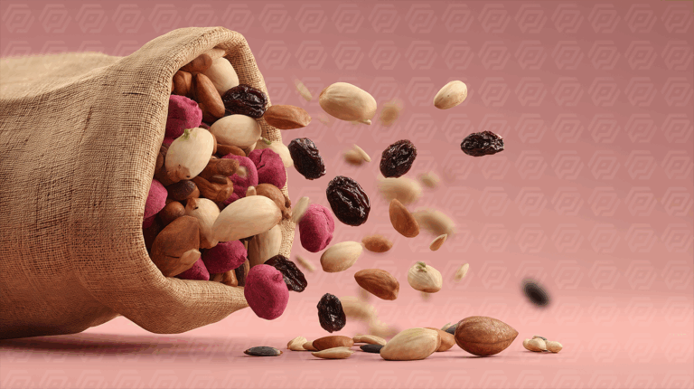 Healthy Nut Mix and Raisins Pouring From Sack on Pink Surface