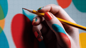 Hand Holding Pencil With Colorful Nail Art Over Abstract Background