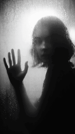 Woman in Shadow Touching Steamy Glass Surface